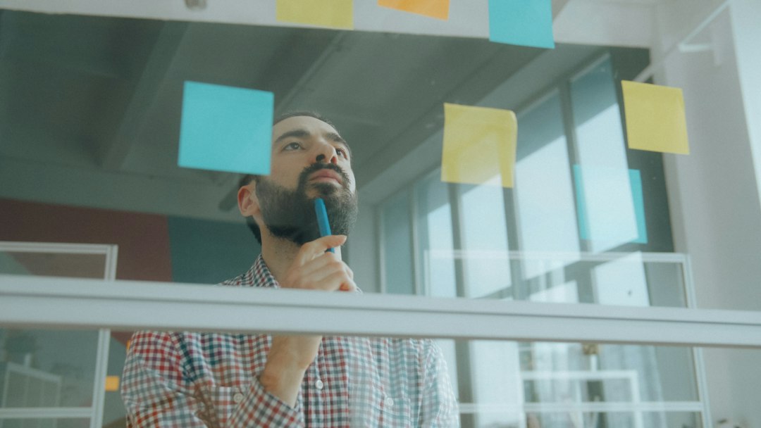 A professional in a modern office drawing a complex flow chart on a clear glass wall, representing the deliberate process of an engineered content strategy.
